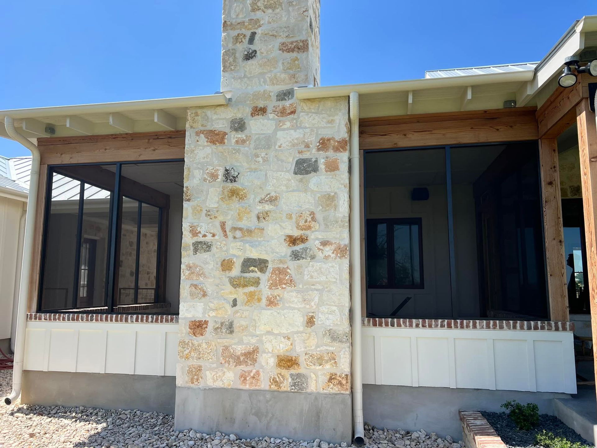 A house with a screened in porch and a stone chimney.