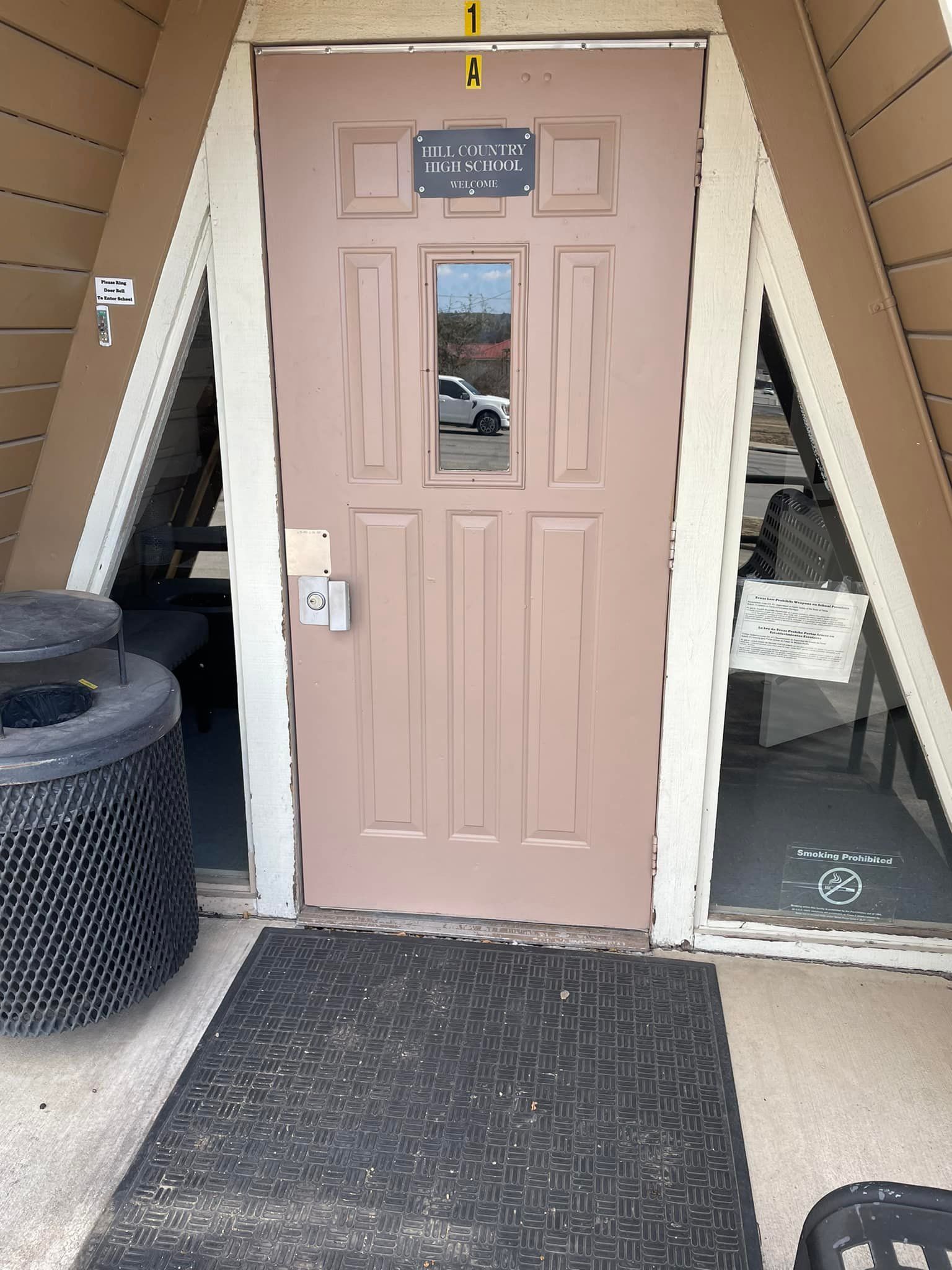 A pink door with a black mat in front of it.