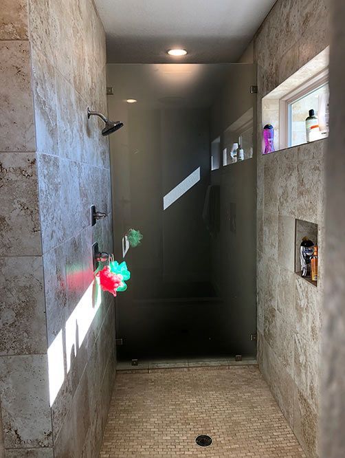 A bathroom with a walk in shower and a window.