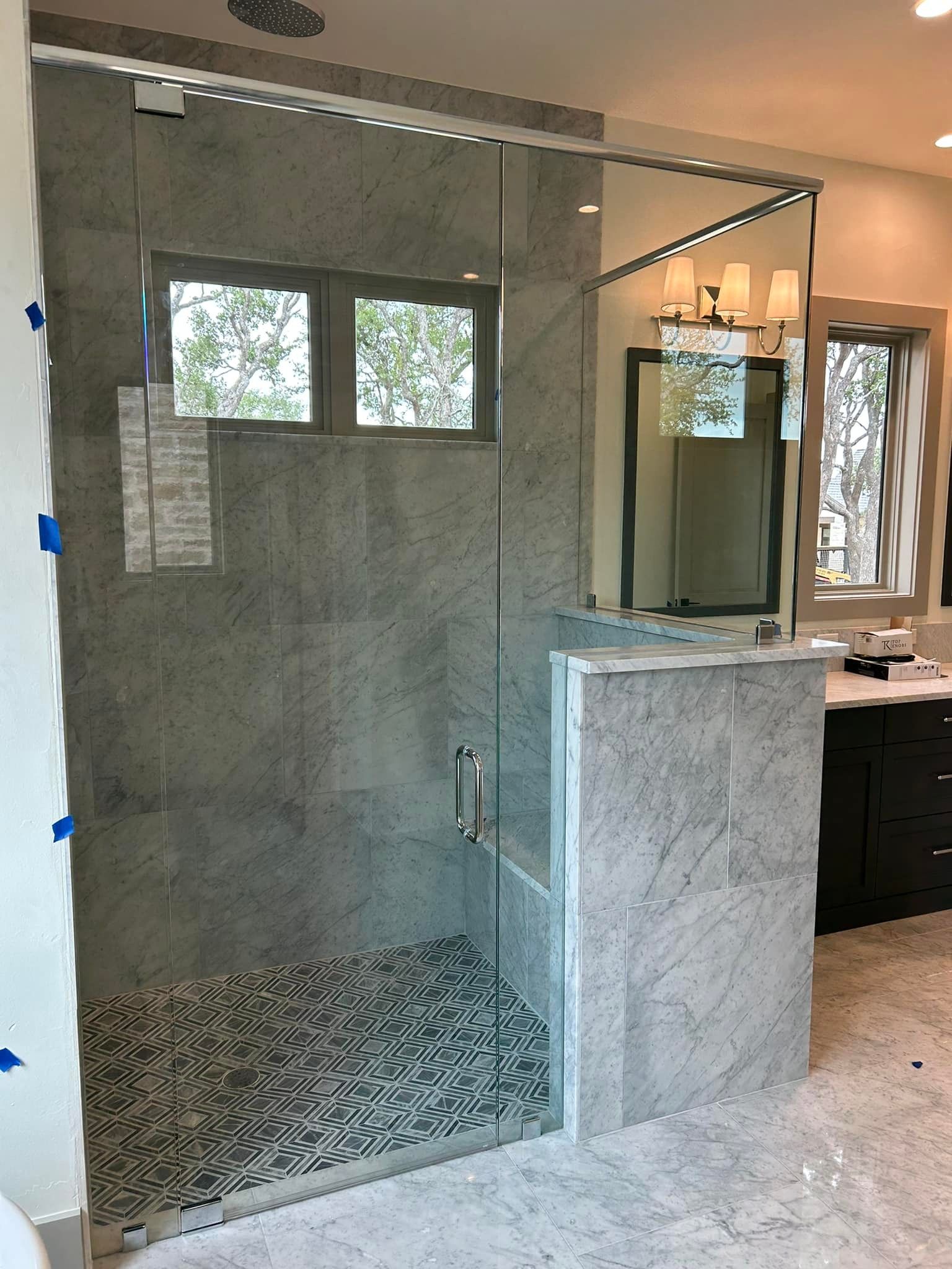 A bathroom with a walk in shower with a glass door.
