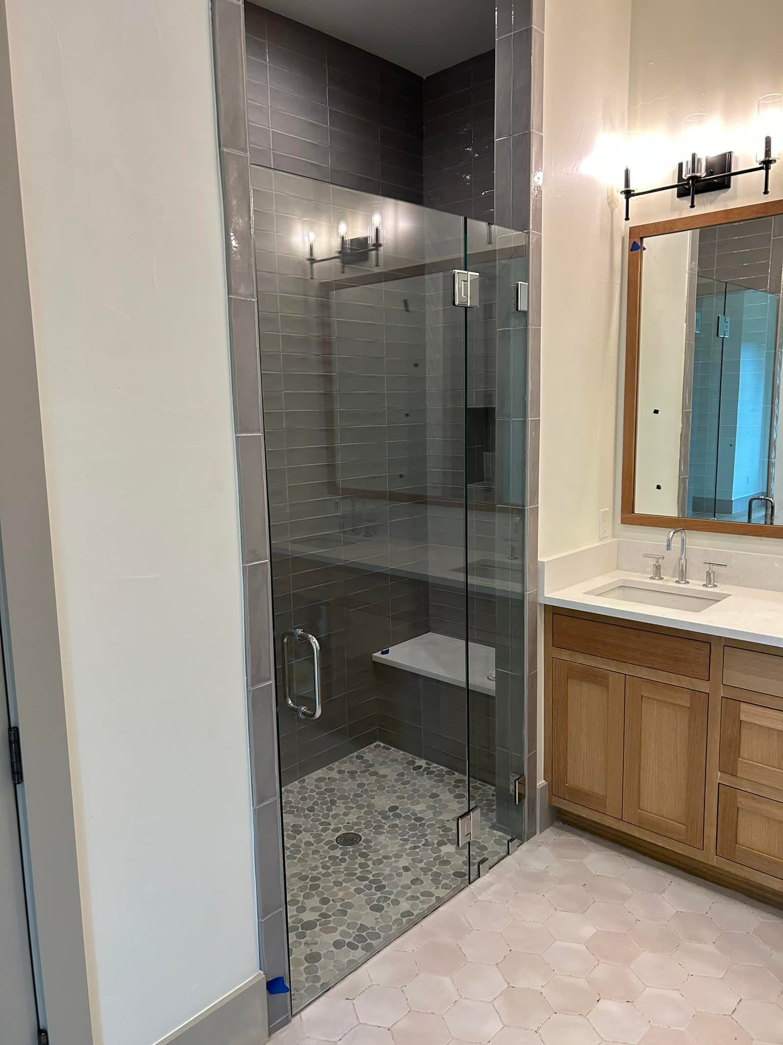 A bathroom with a walk in shower , sink and mirror.