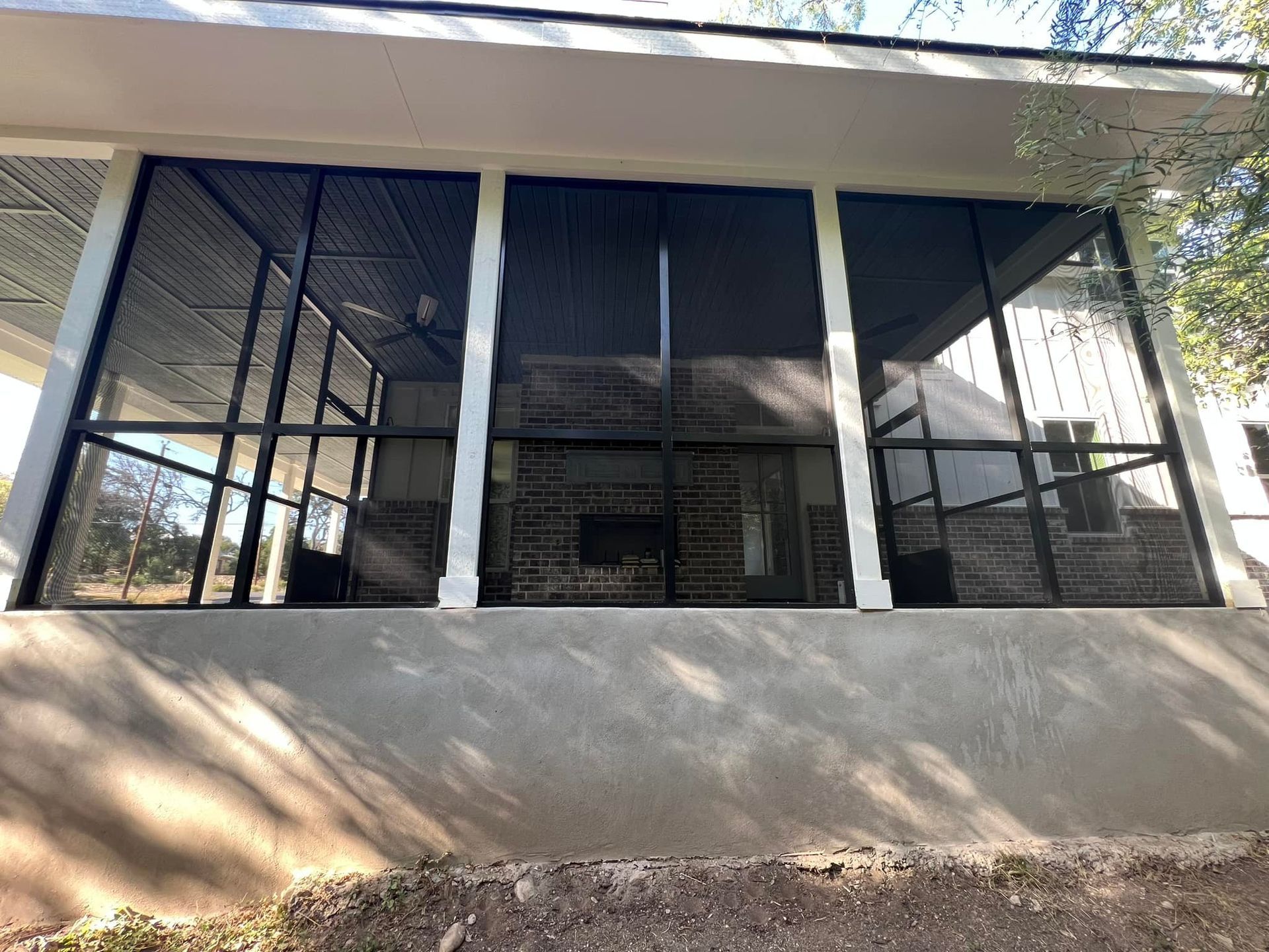 A screened in porch with a lot of windows and a fireplace.