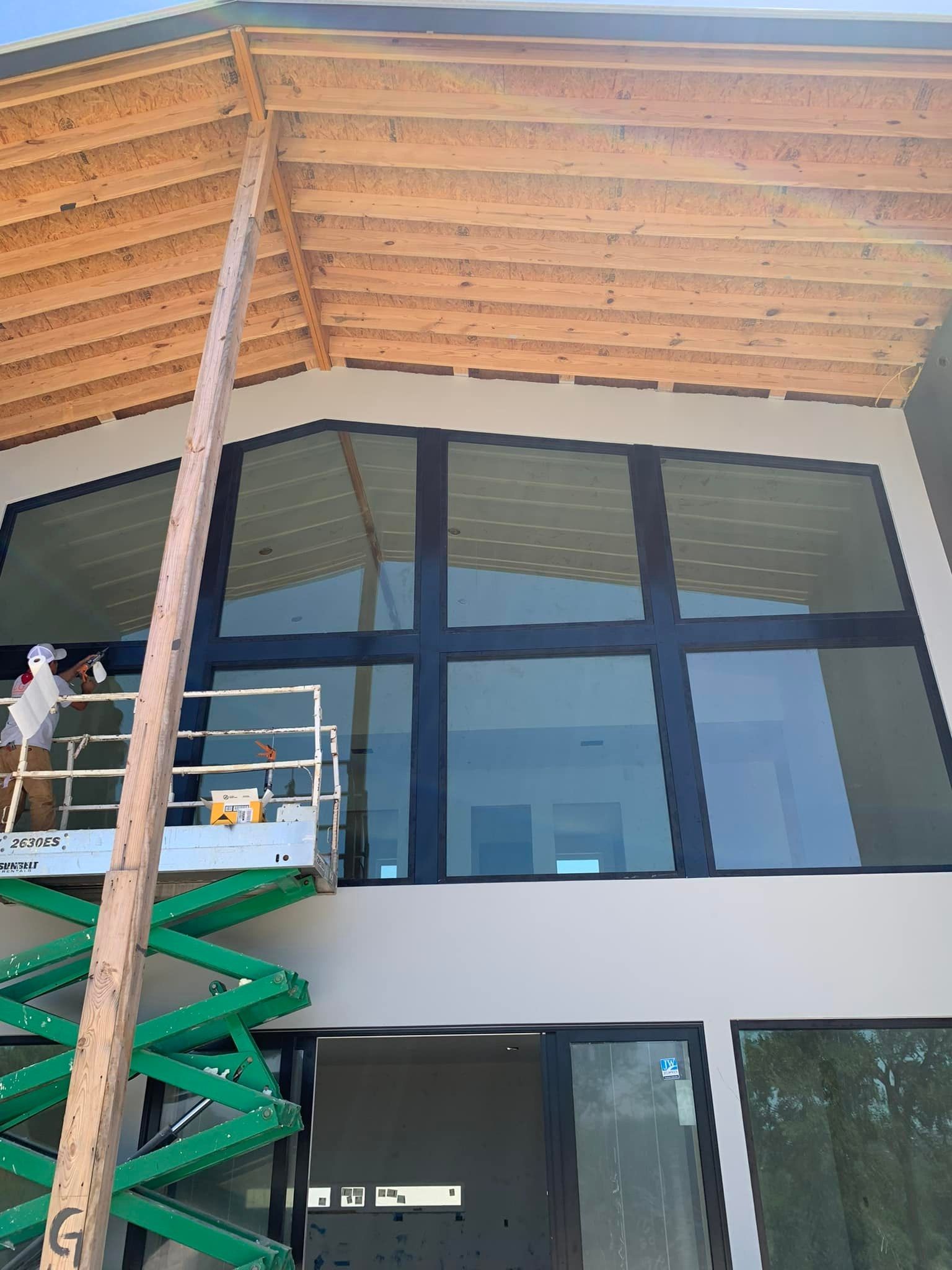 A man is standing on a scissor lift on the side of a building.