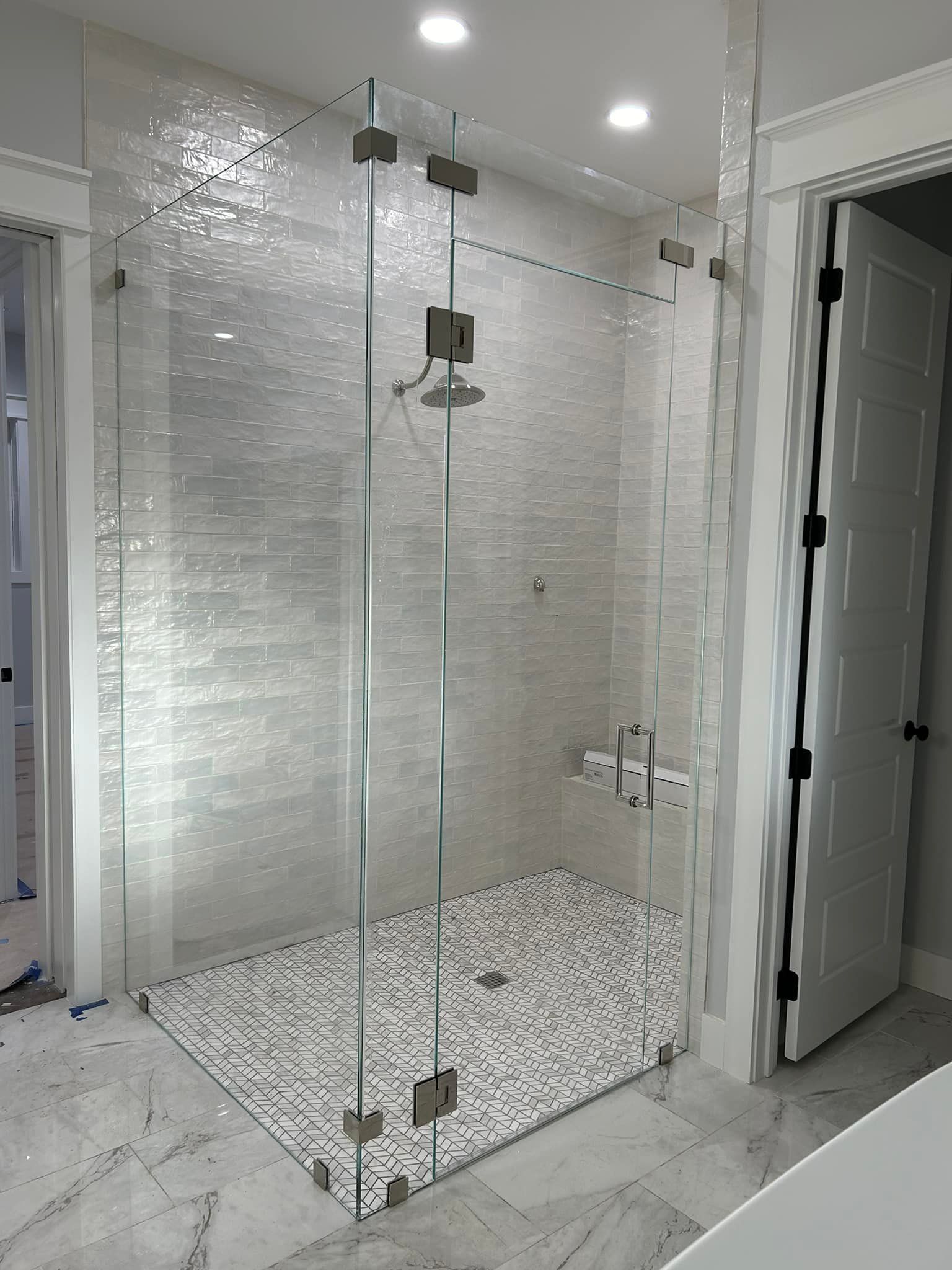 A bathroom with a walk in shower with a glass door.