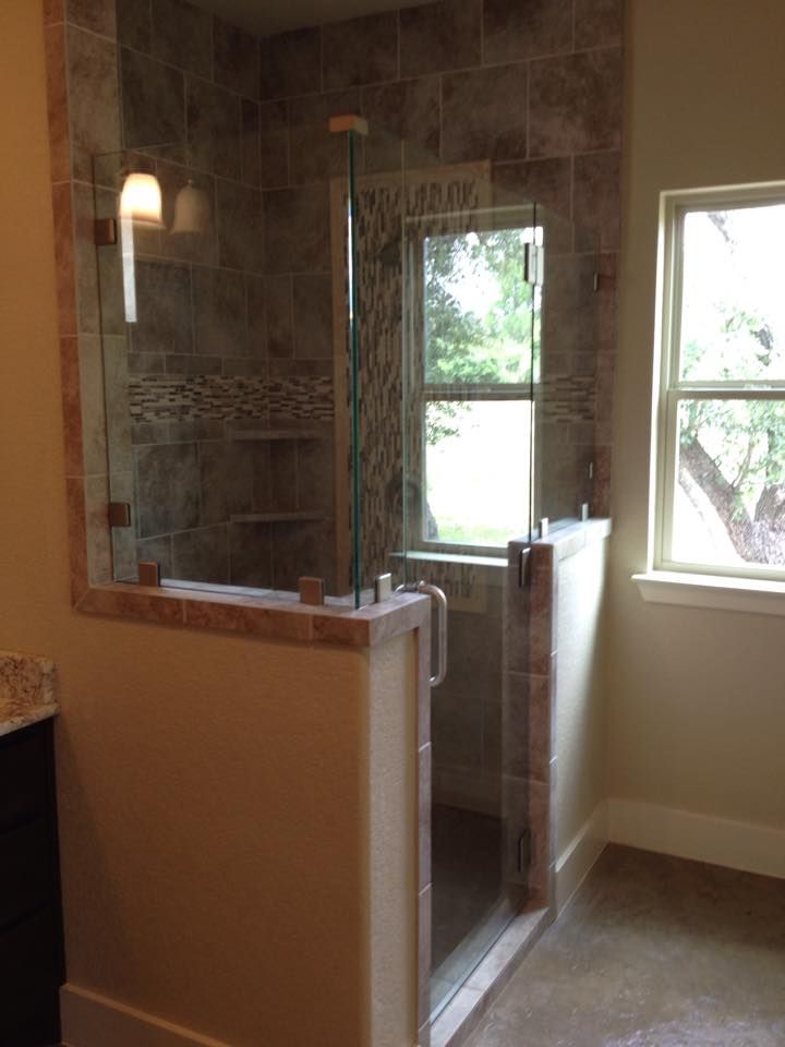 A bathroom with a walk in shower and a window.