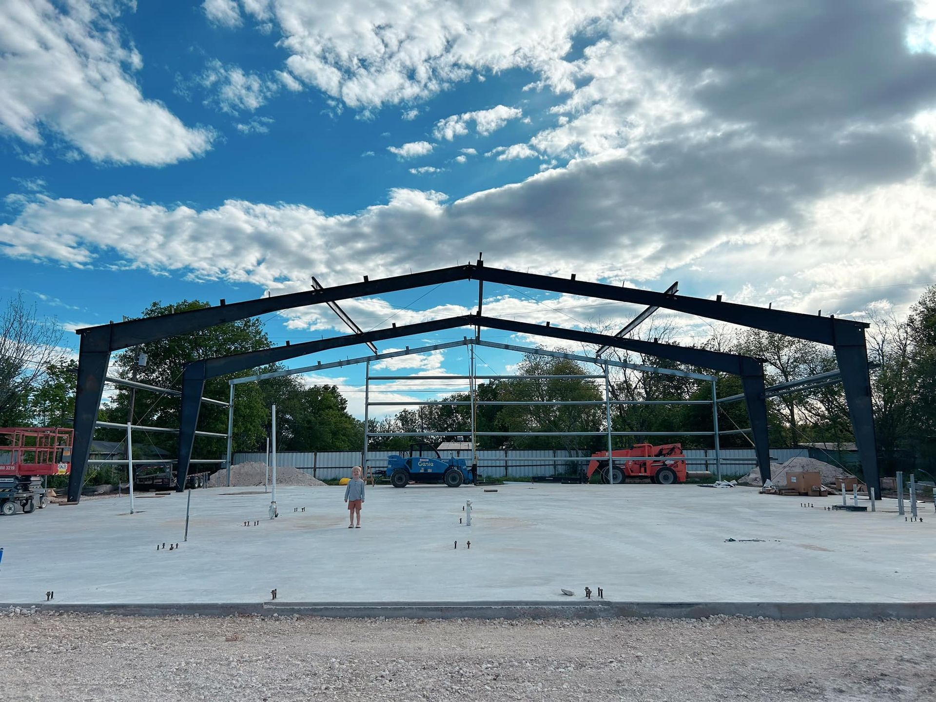A large building under construction with a blue sky and clouds in the background.