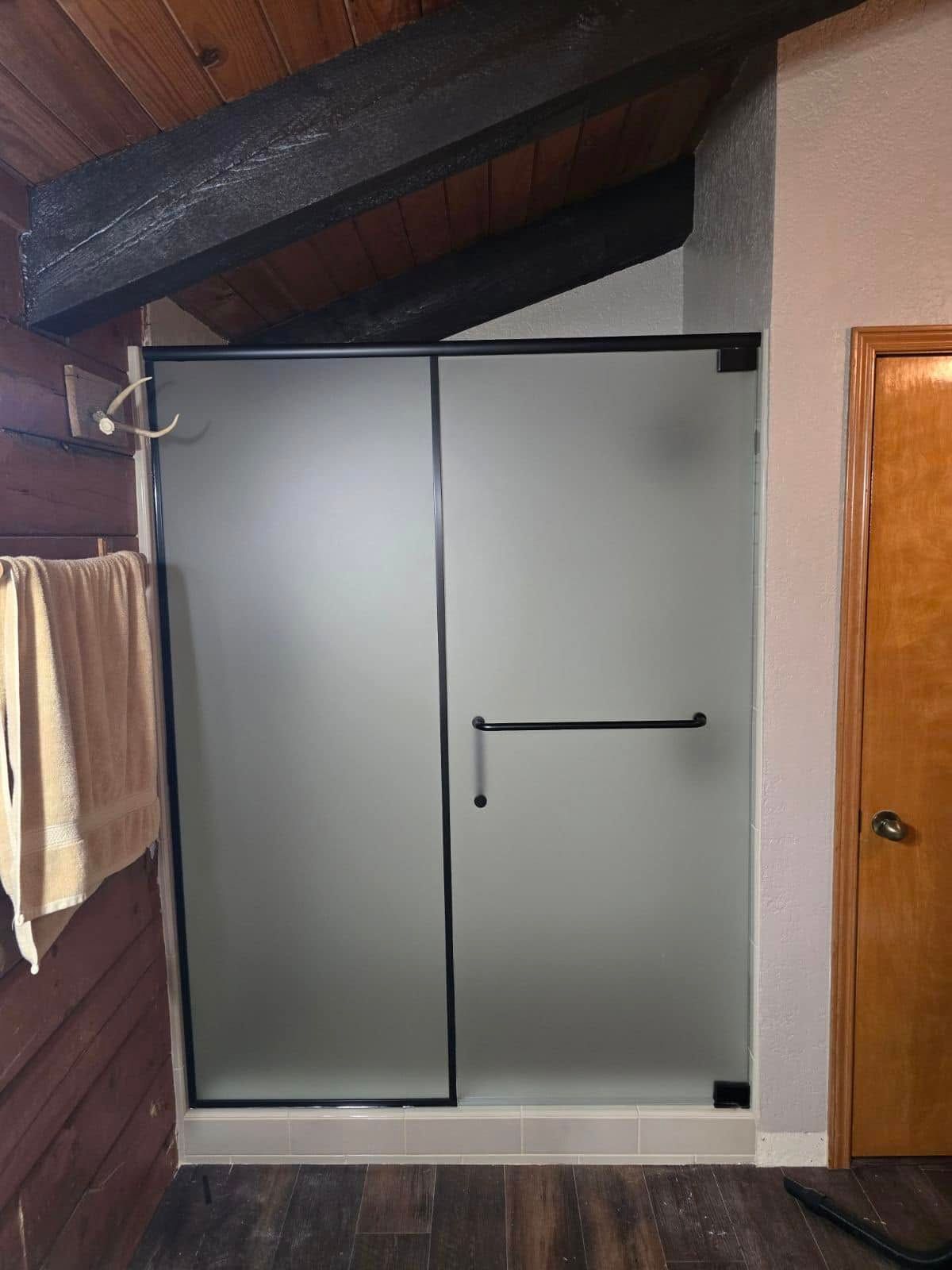 A bathroom with a walk in shower with a frosted glass door.