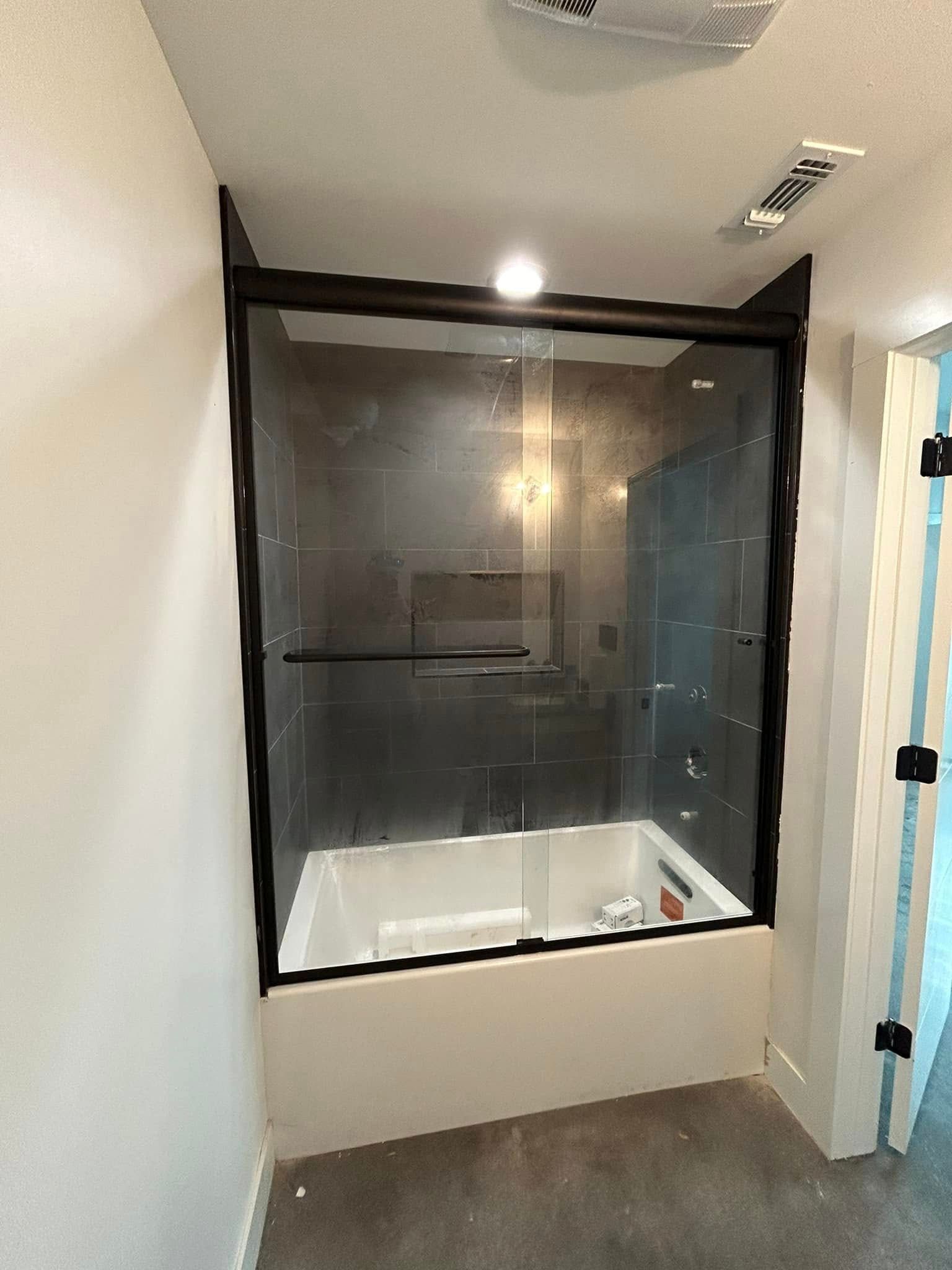 A bathroom with a bathtub and a glass shower door.