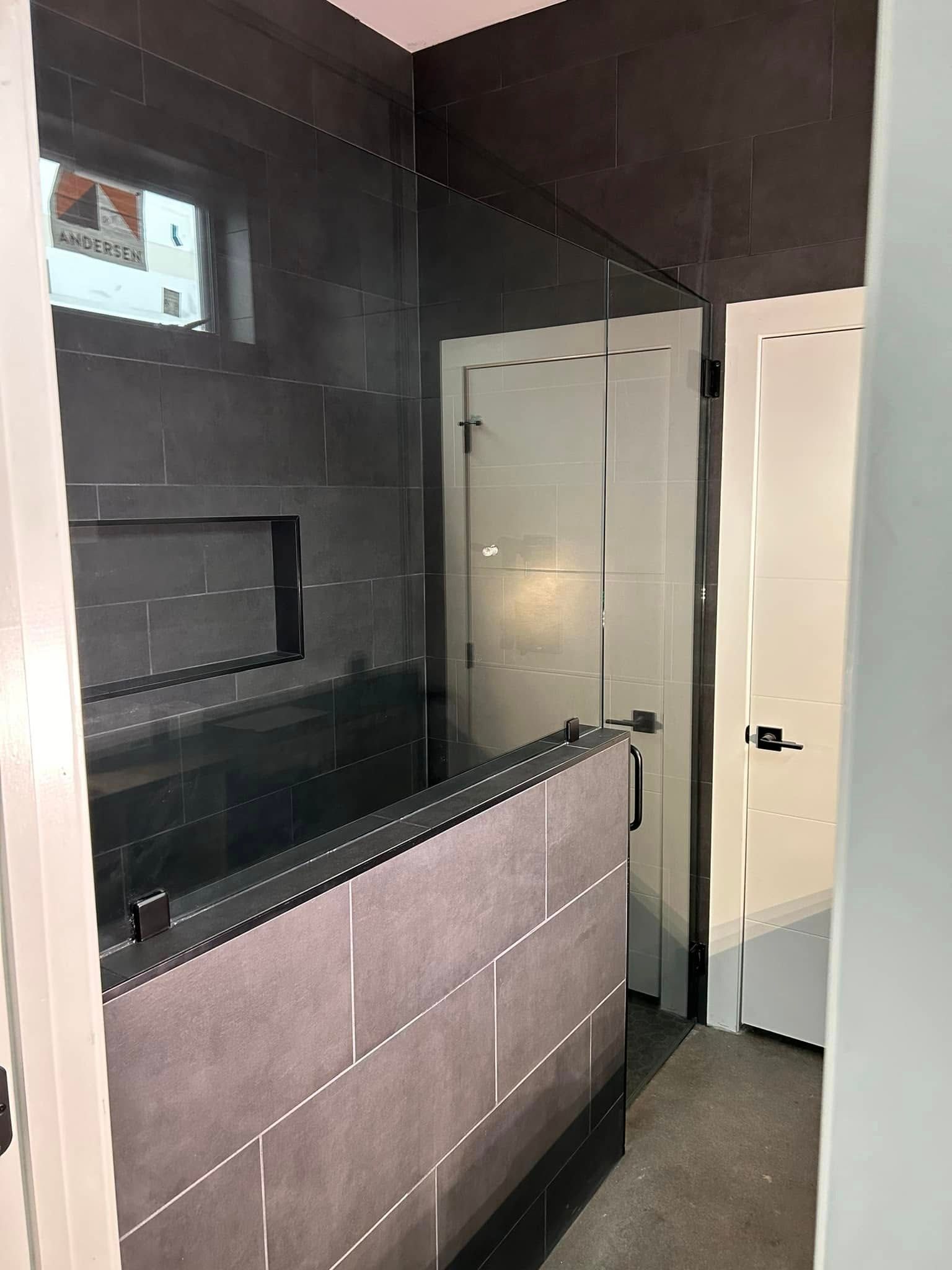 A bathroom with a glass shower door and a window.