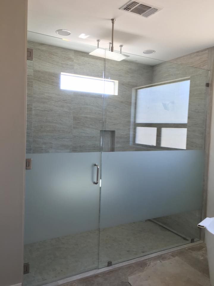 A bathroom with a glass shower door and a window.