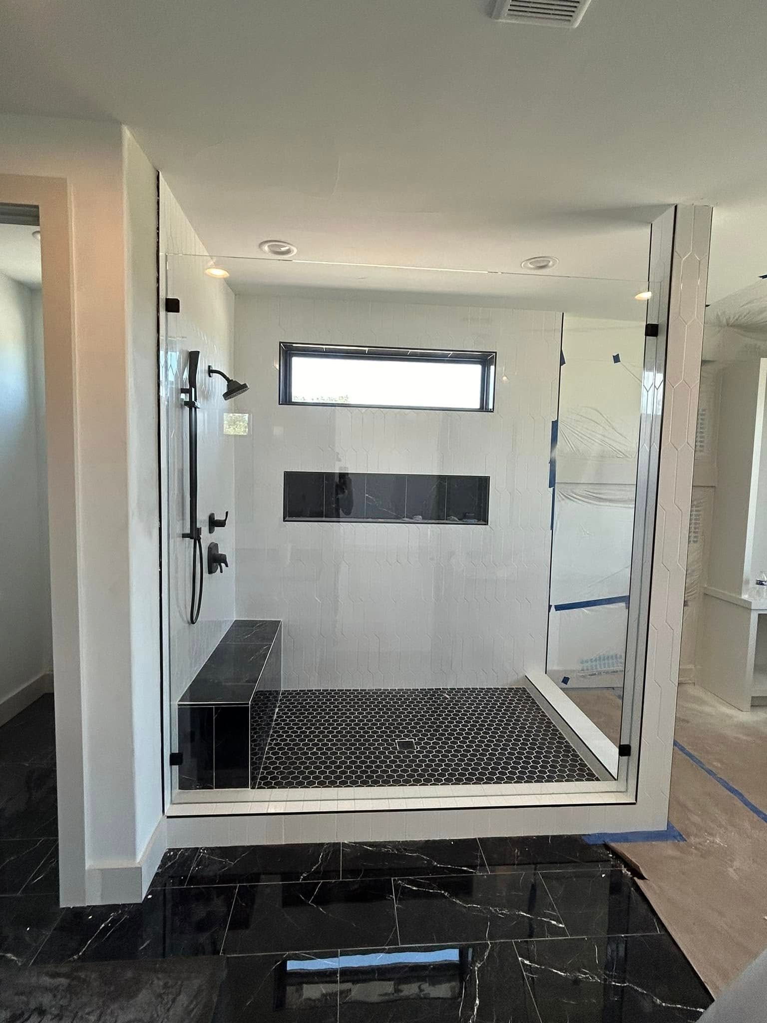 A bathroom with a walk in shower and a window.