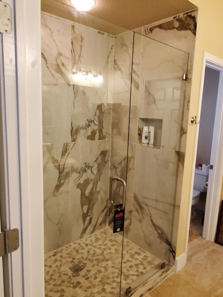 A bathroom with a walk in shower with a glass door.