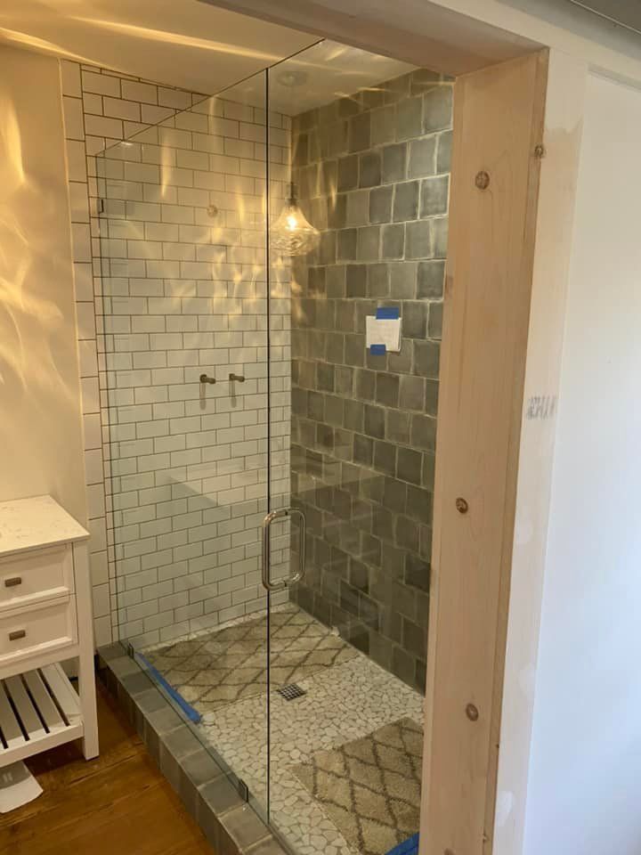 A bathroom with a walk in shower with a glass door.