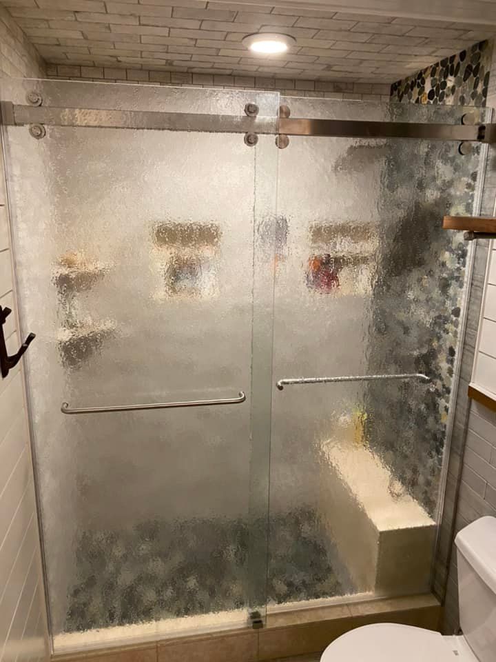 A bathroom with a sliding glass shower door and a toilet.