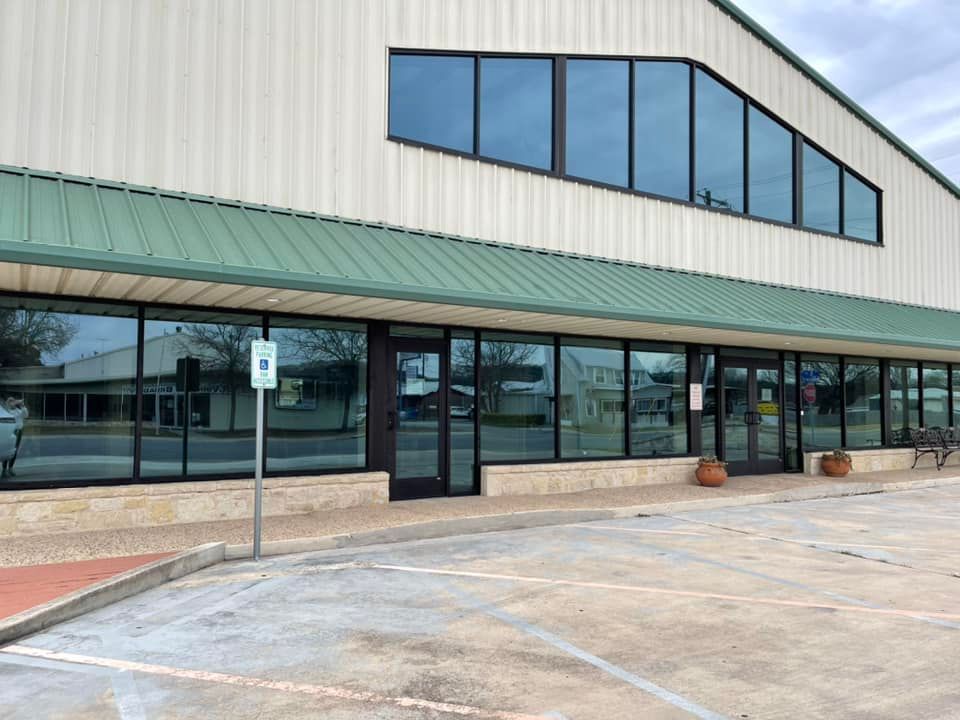 A large building with a green roof and a parking lot in front of it.