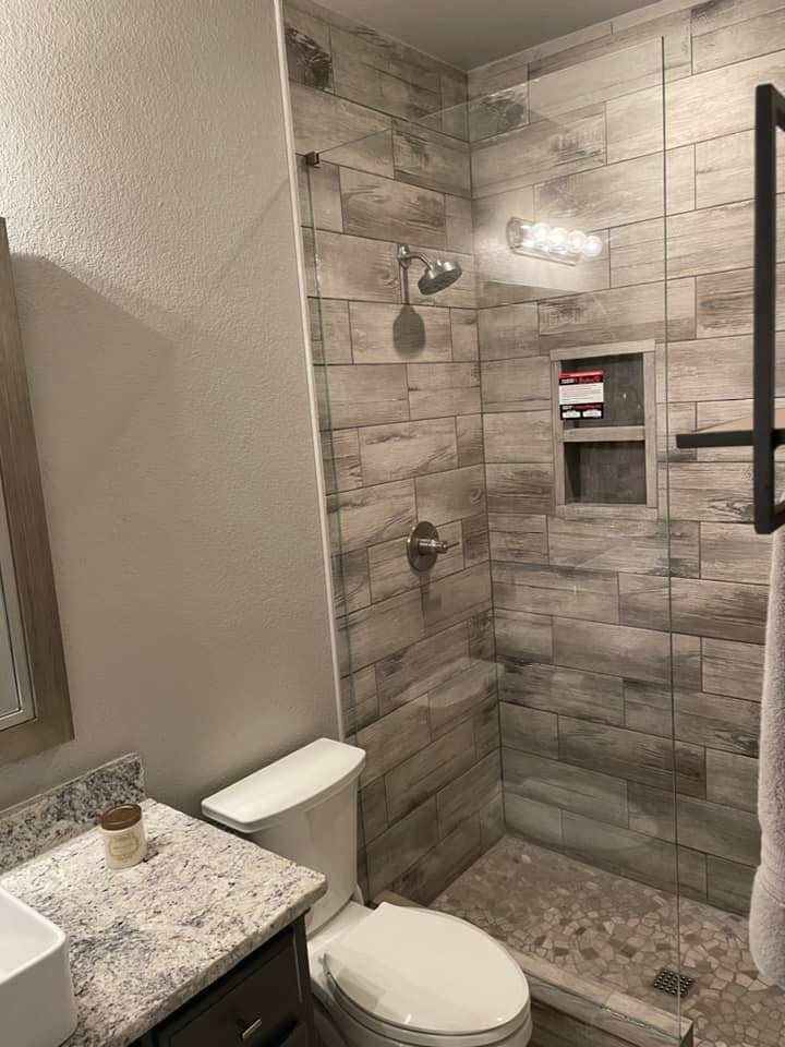 A bathroom with a toilet , sink and walk in shower.