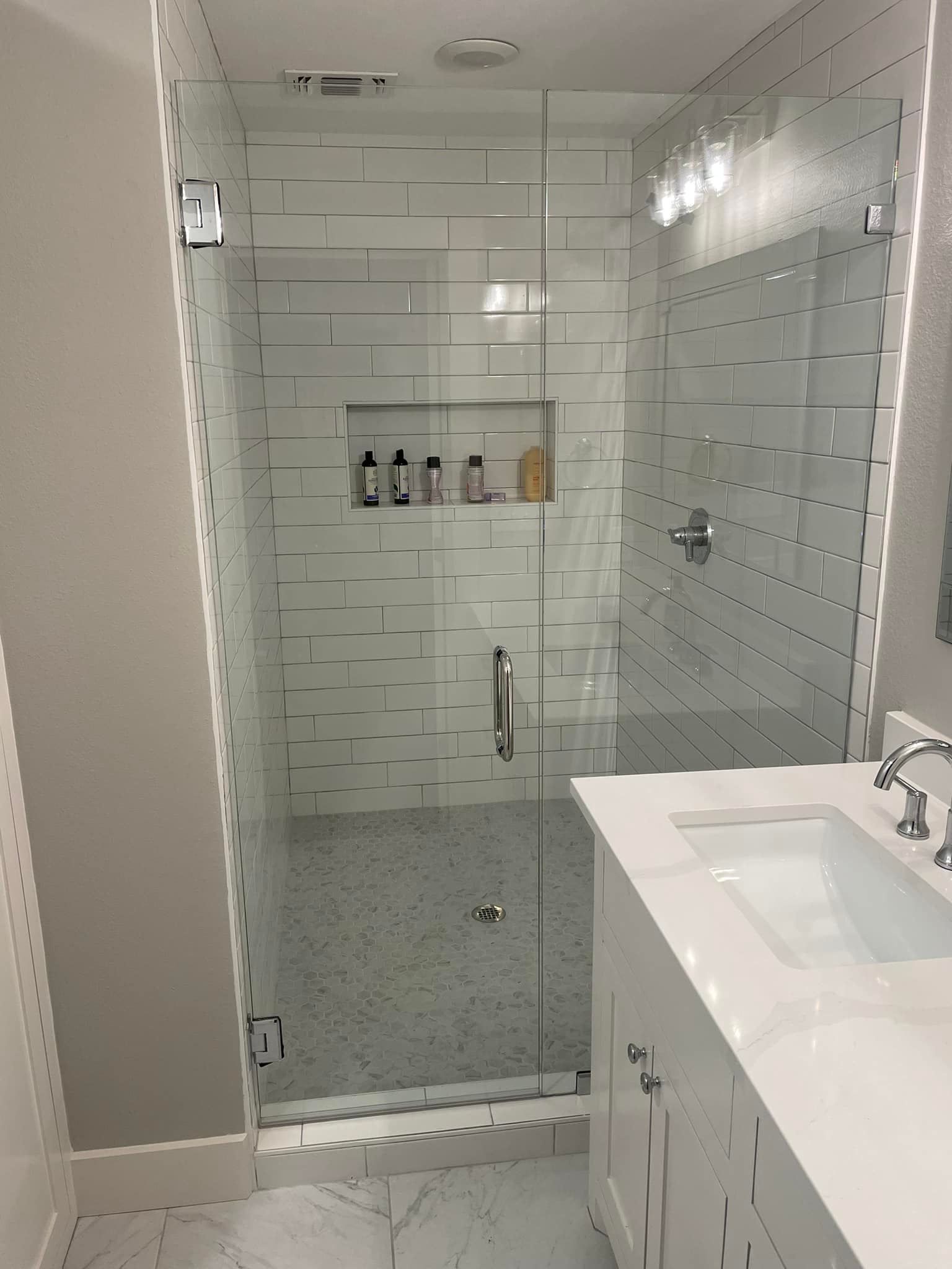 A bathroom with a walk in shower and a sink