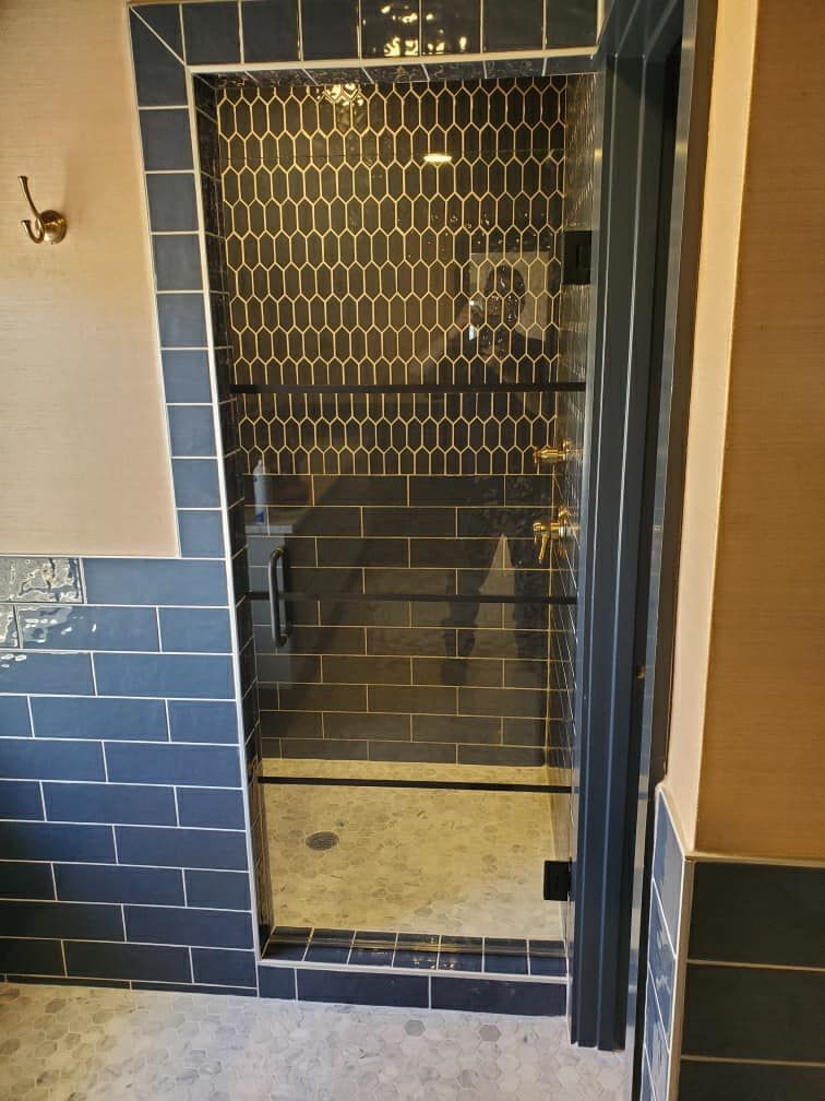 A bathroom with blue tiles and a glass shower door.