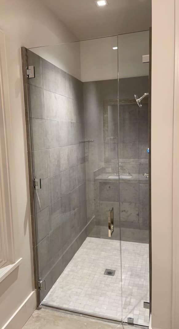 A bathroom with a walk in shower with a glass door.