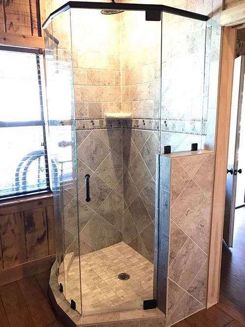 A bathroom with a walk in shower with a glass door.