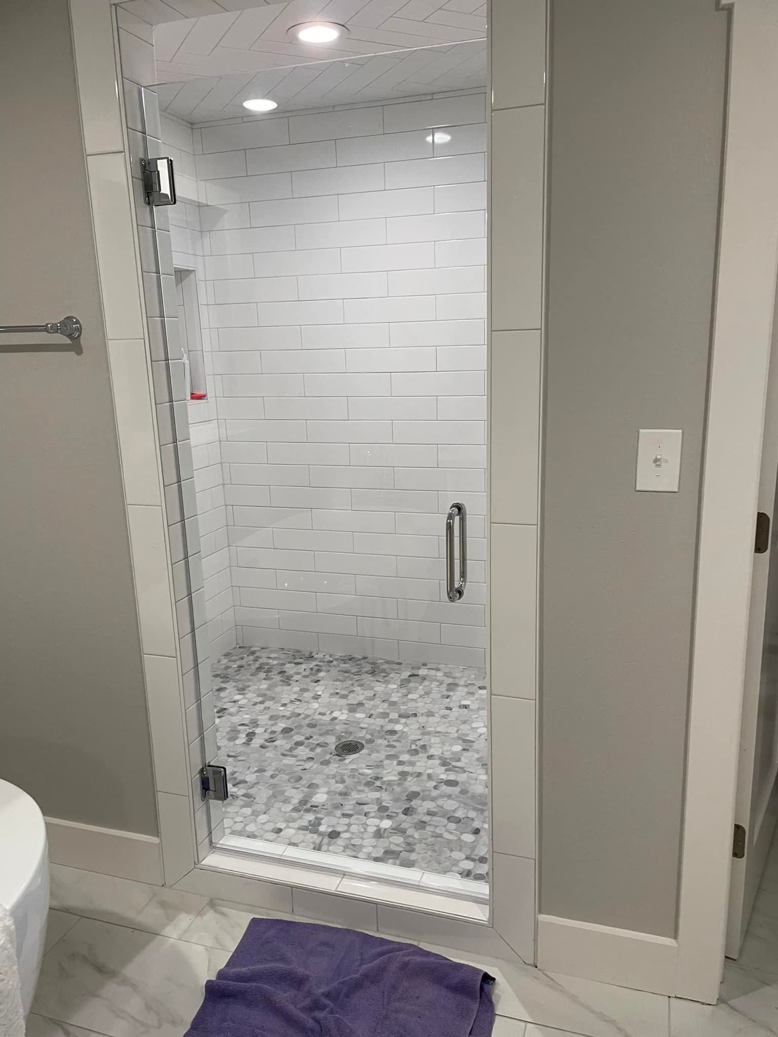 A bathroom with a walk in shower with a glass door.