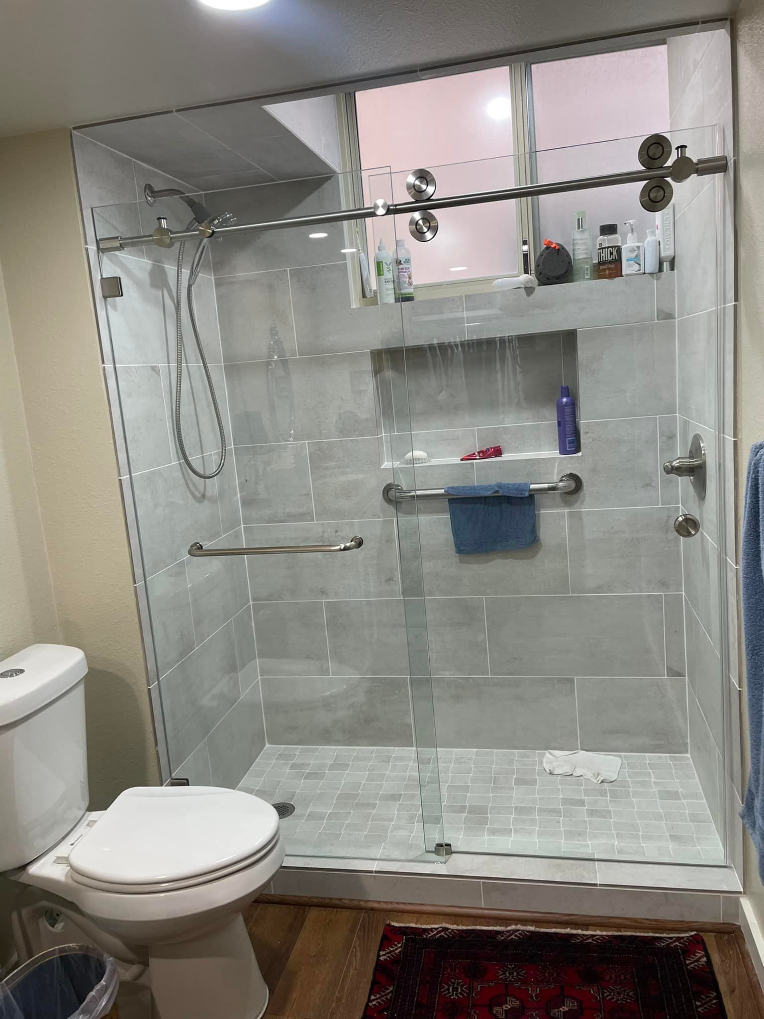 A bathroom with a toilet , shower , and sliding glass door.