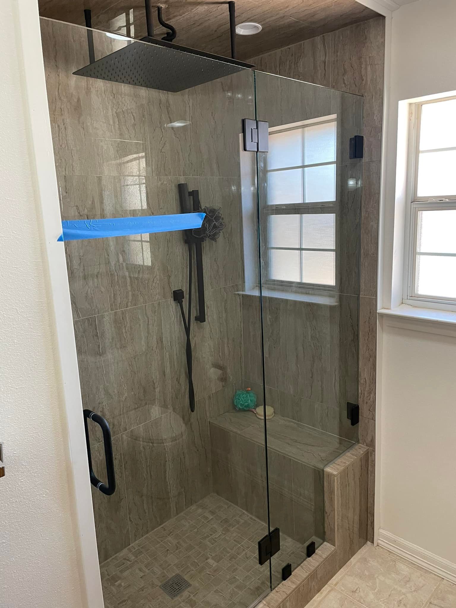 A bathroom with a walk in shower and a window.