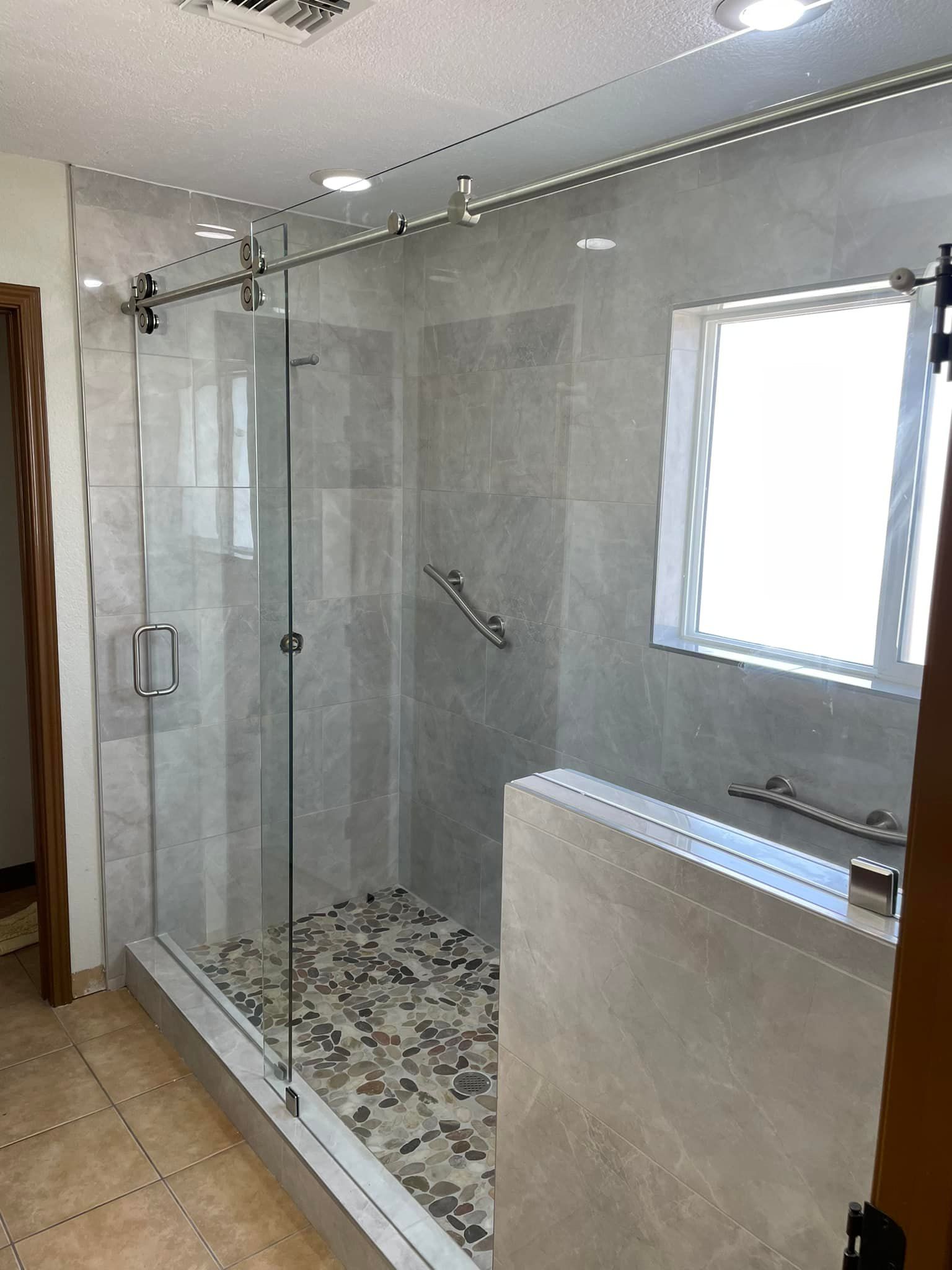 A bathroom with a sliding glass shower door and a window.