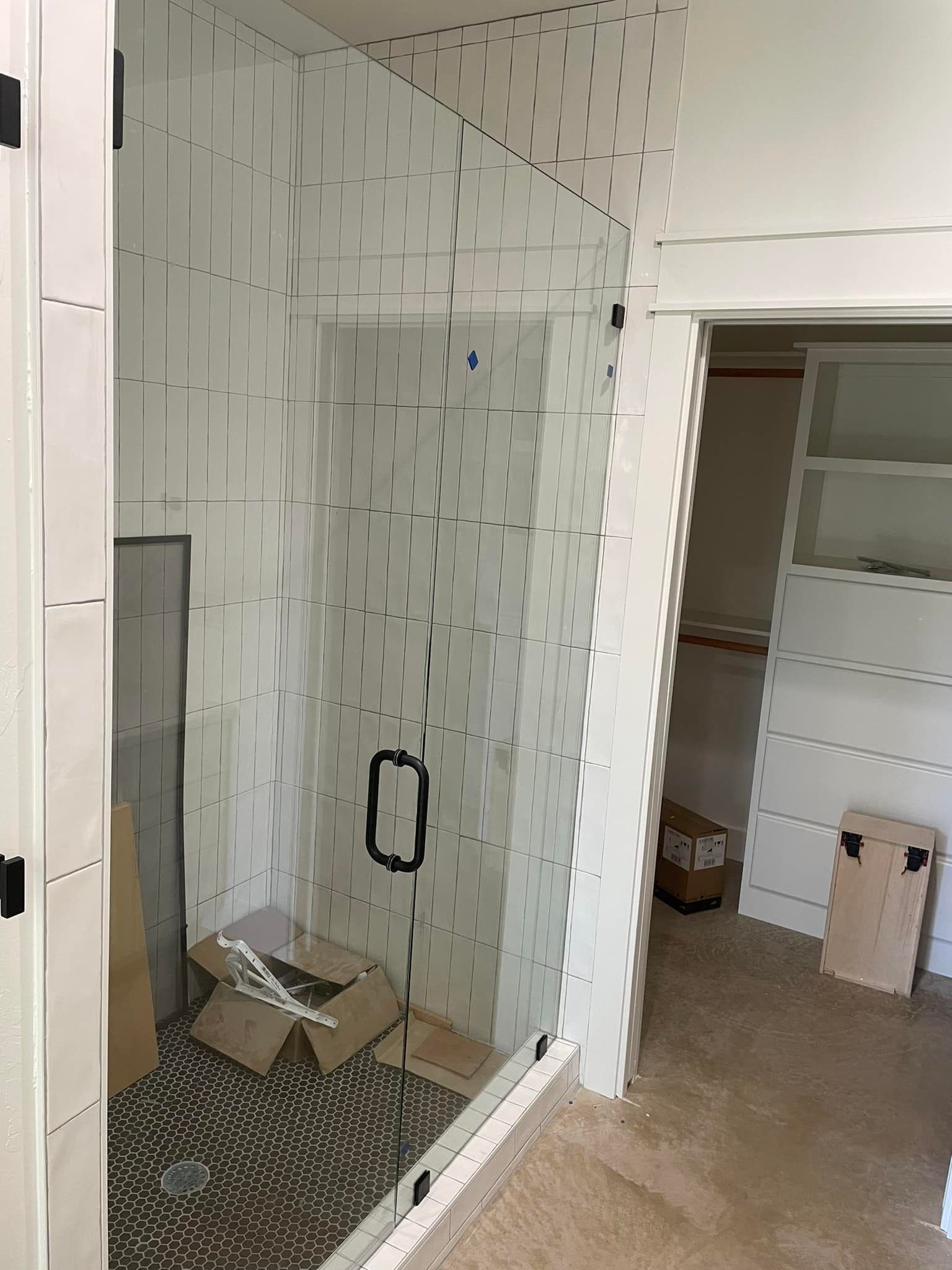 A bathroom with a walk in shower and a closet.