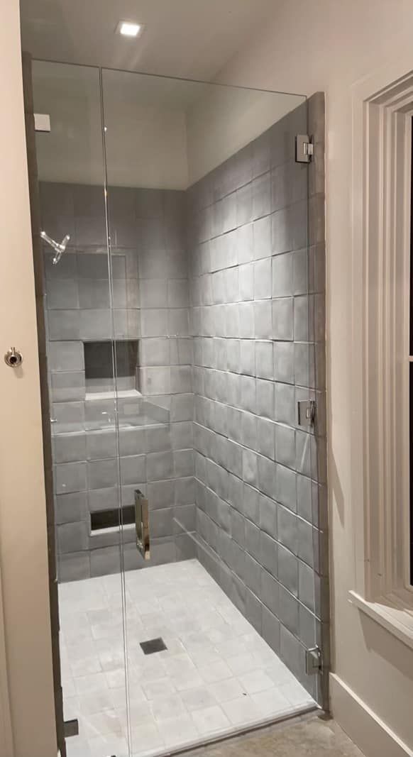 A bathroom with a walk in shower with a glass door.