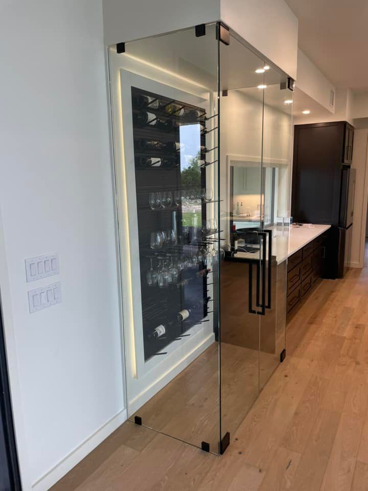 A kitchen with a glass door leading to a wine cellar.
