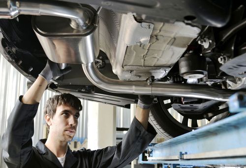 Mechanic inspecting car underside on a lift in an auto repair shop