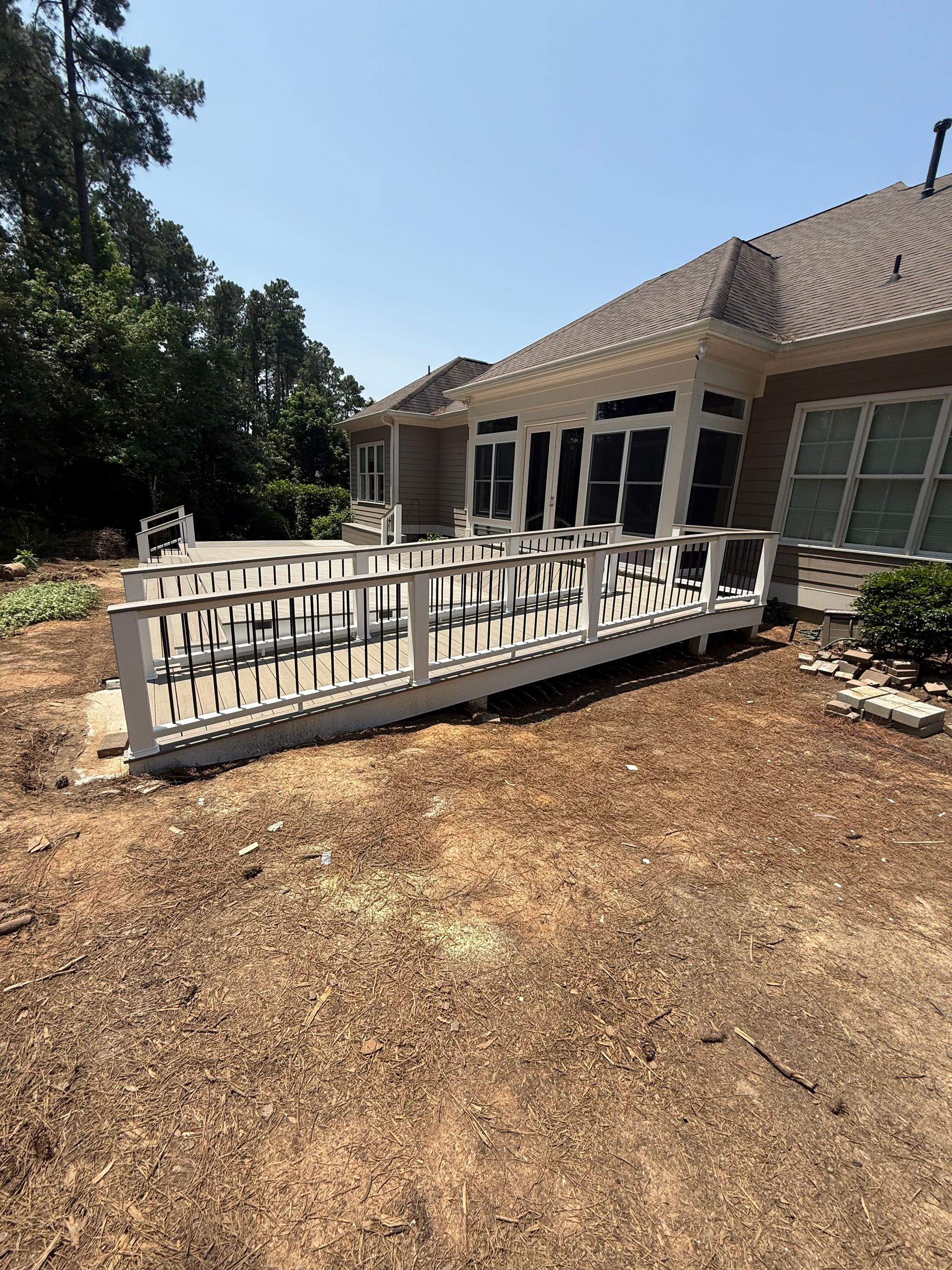 White deck with ramp against beige house on a sunny day.