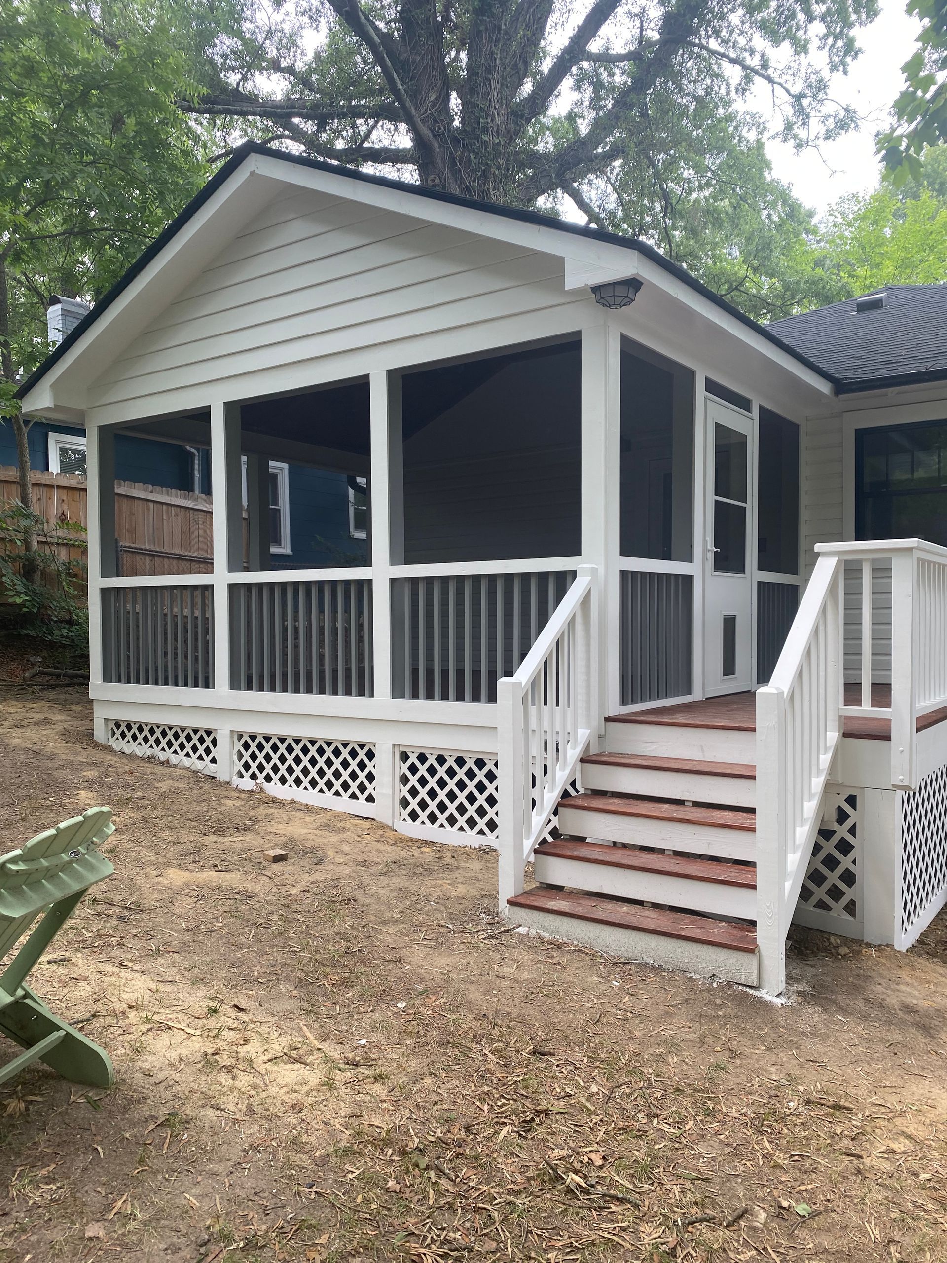 White screened-in porch with steps, lattice base, and wooden steps. Brown and white exterior with a backyard setting.