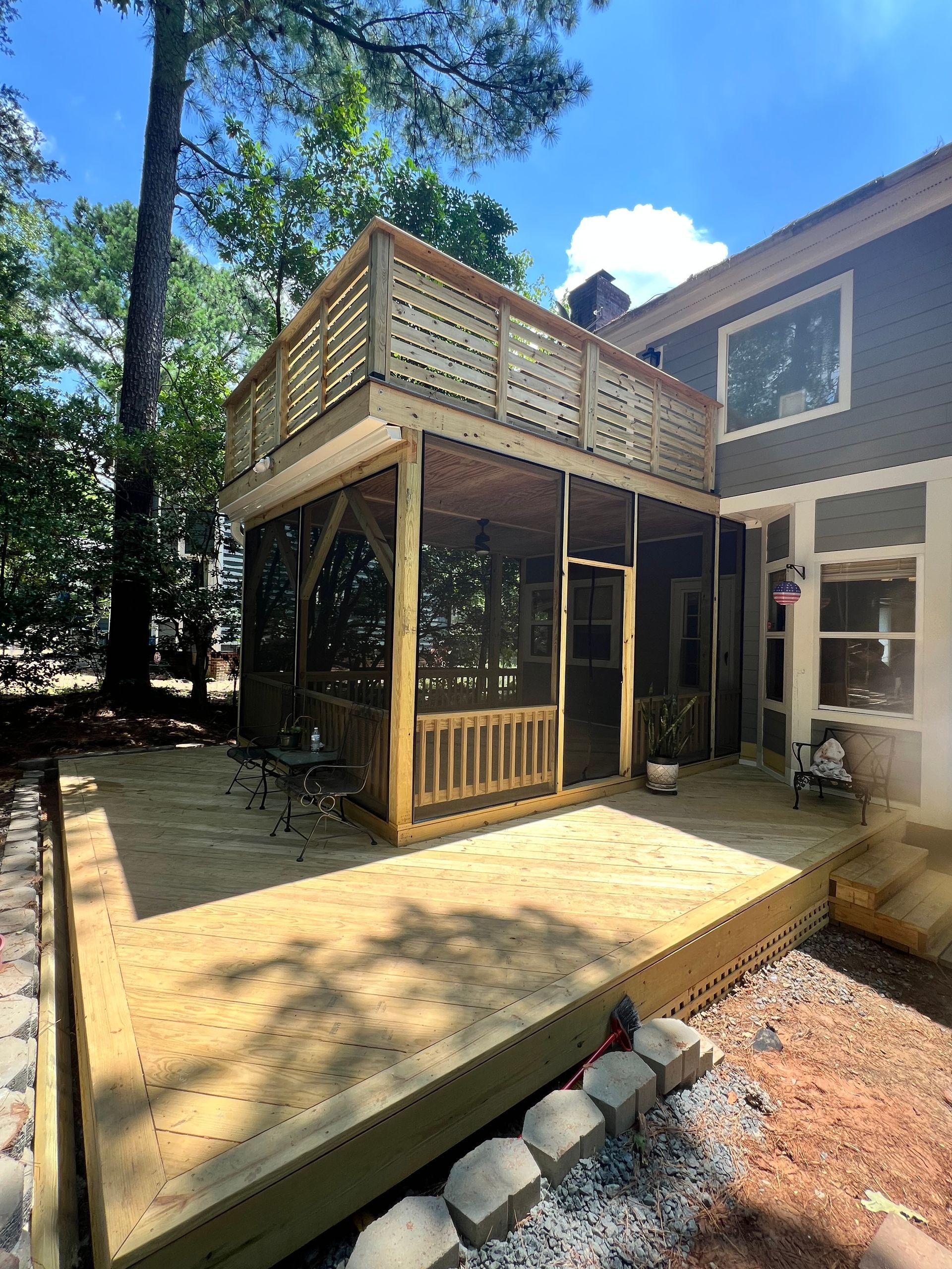 Wooden deck and screened-in porch connected to a house, with a second-story deck above.