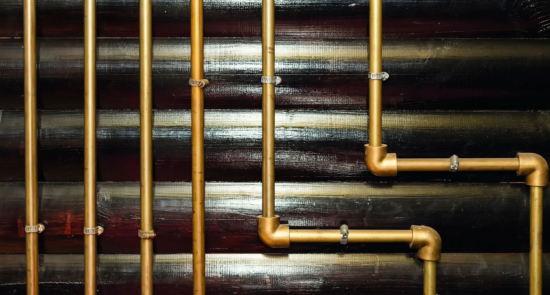 Golden pipes against a dark, textured background, likely a wall.
