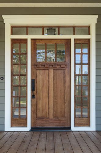 The front door of a house with a wooden door and white trim.