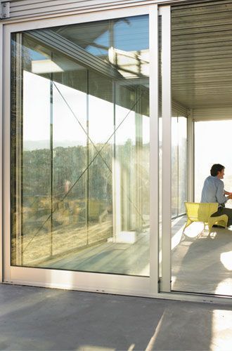 A man is sitting at a table in front of a sliding glass door.