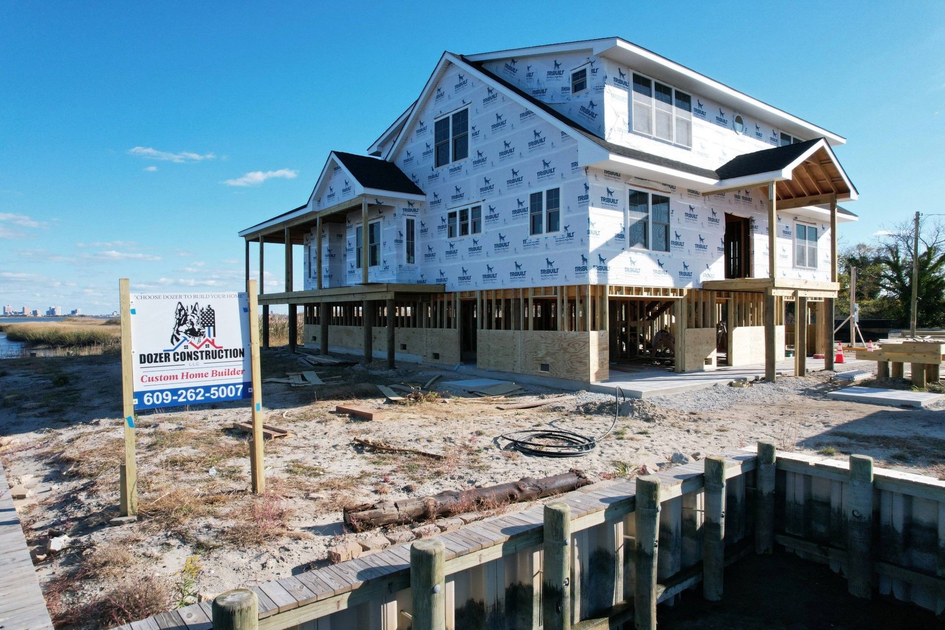 A house is being built on stilts with a for sale sign in front of it.