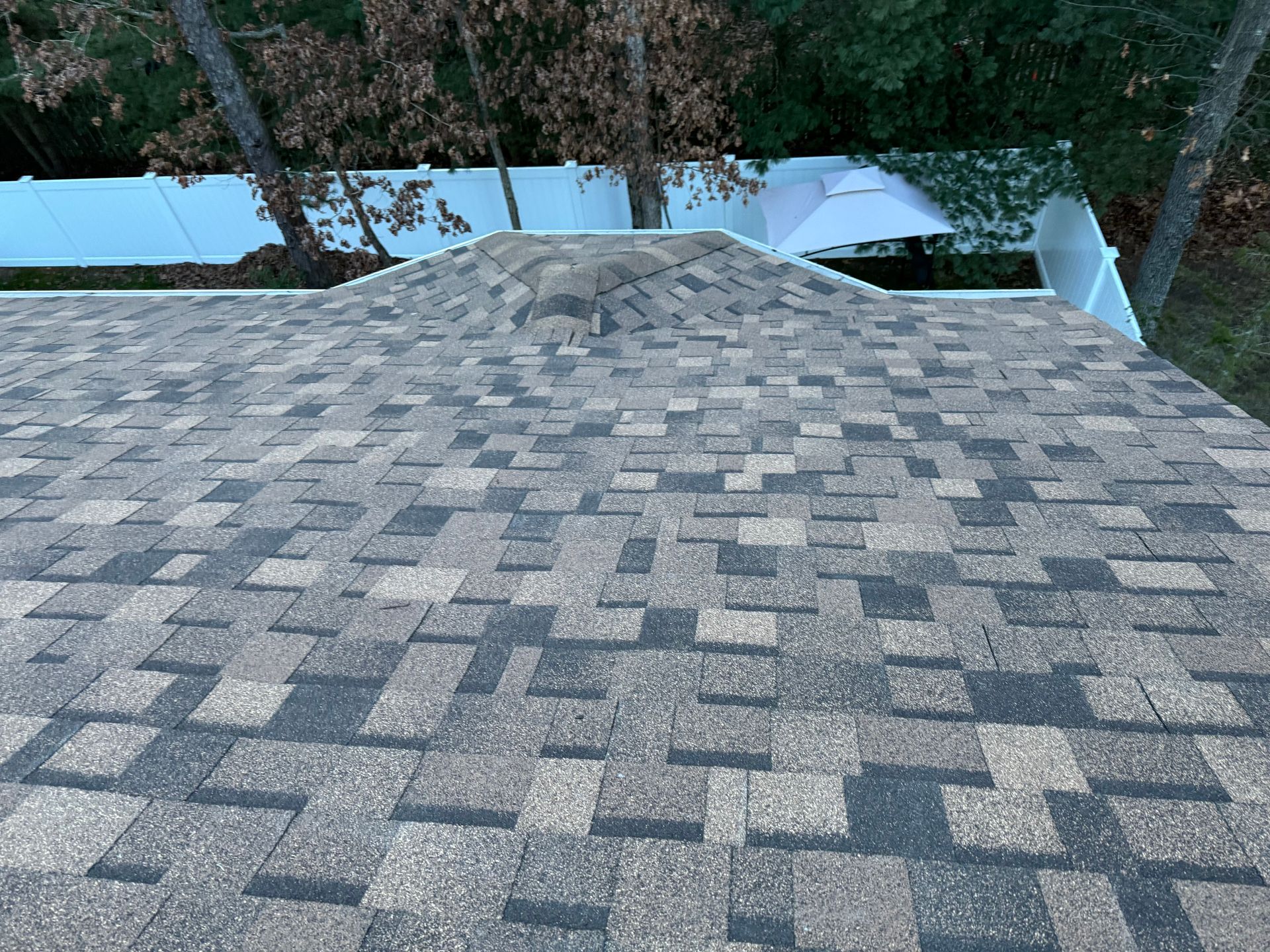 A close up of a roof with a white fence in the background.