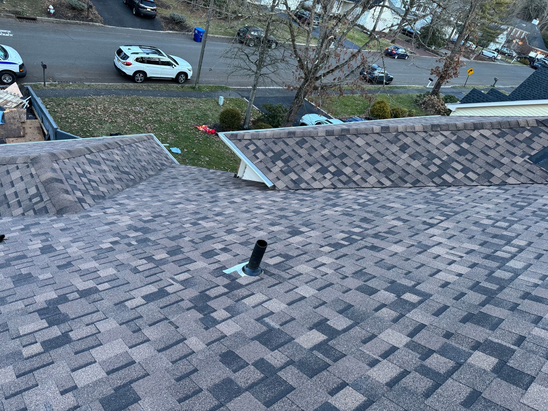 An aerial view of a roof with a car parked on the side of the road.