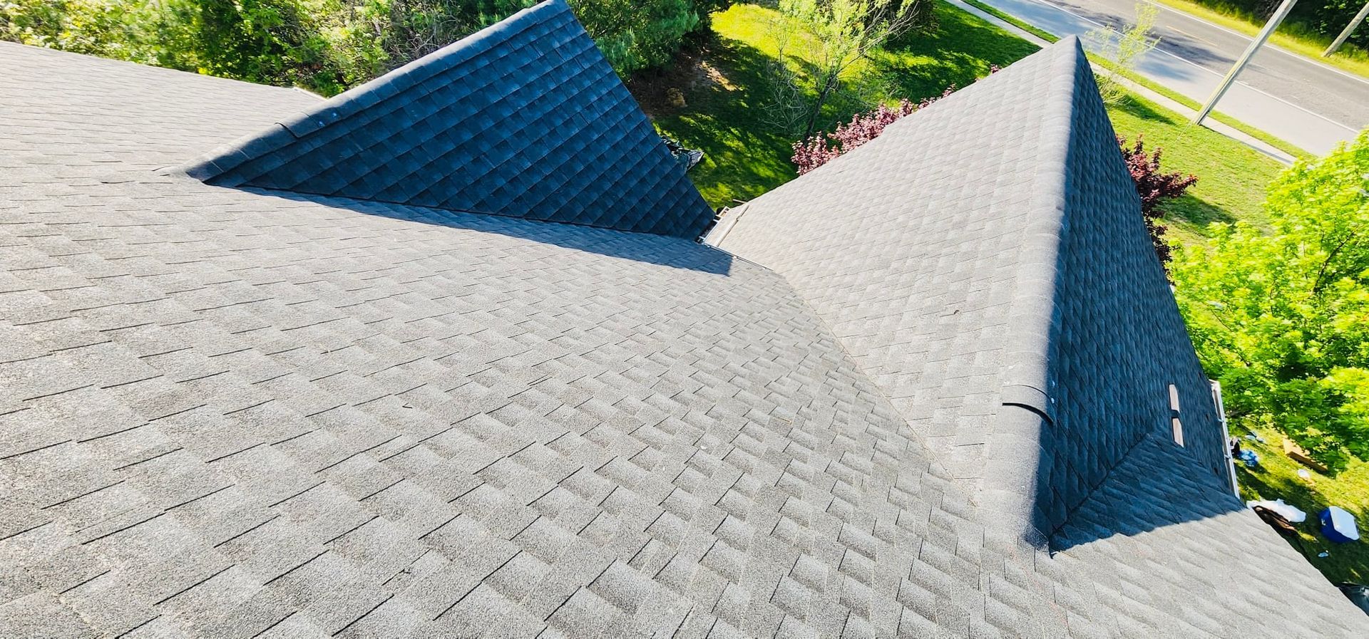 A roof with a lot of shingles on it and trees in the background.