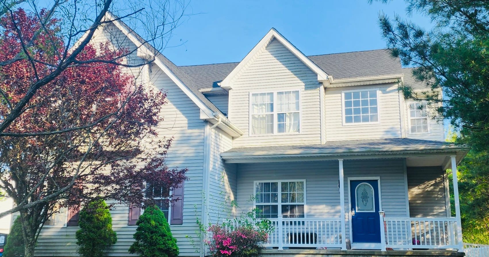 A large white house with a blue door and a porch.