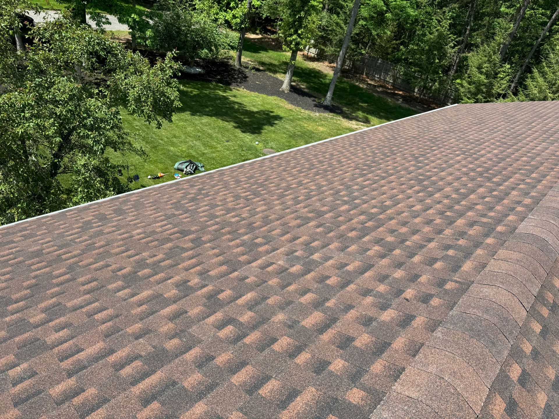 A roof with a lot of shingles on it and trees in the background.