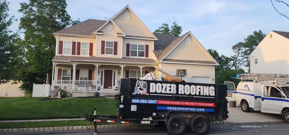 A dozer roofing trailer is parked in front of a house.