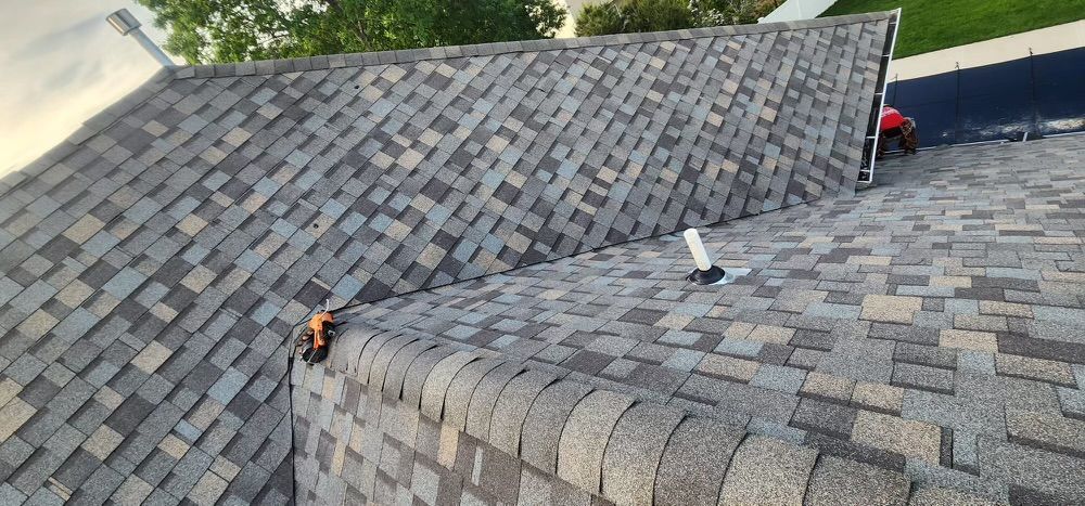 A close up of a roof with shingles being installed on a house.