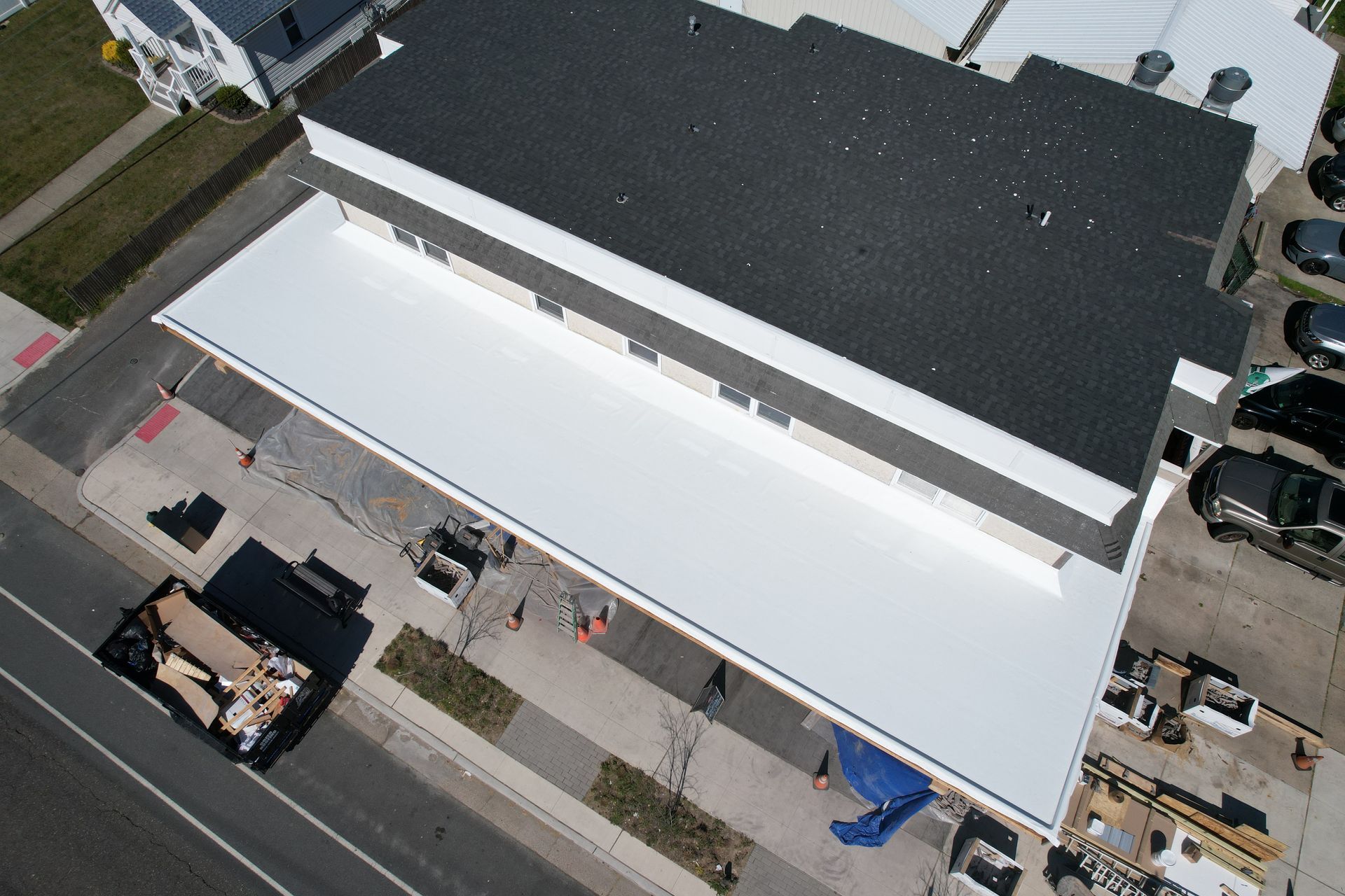 An aerial view of a white building with a black roof