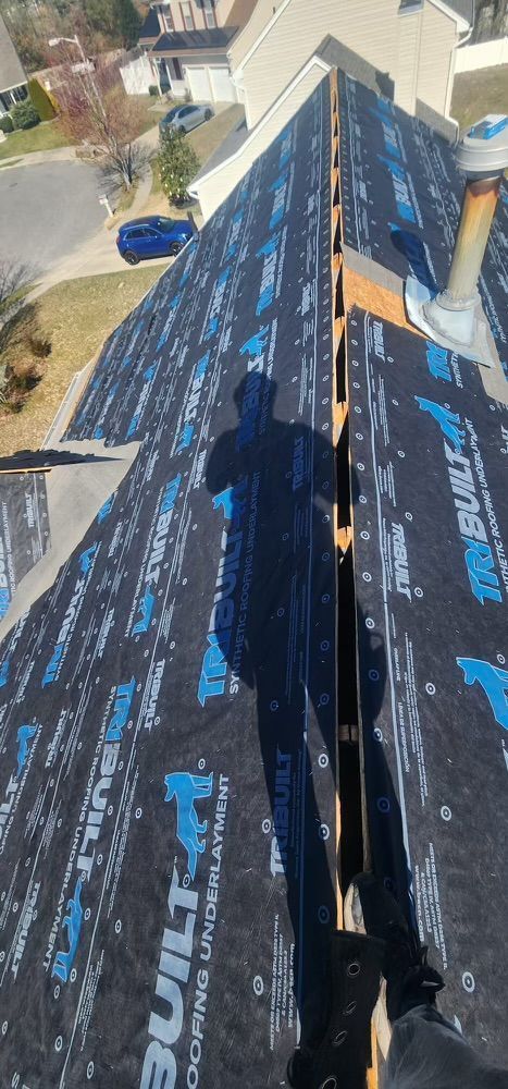 A person is standing on top of a roof with a shadow on it.