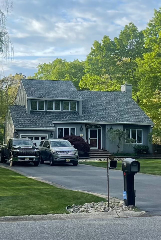 A couple of cars are parked in front of a house.