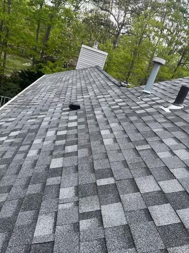 A roof with a lot of shingles on it and trees in the background.
